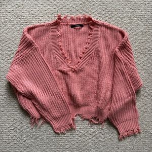 Cropped pink knit sweater with distressed hem and cuffs